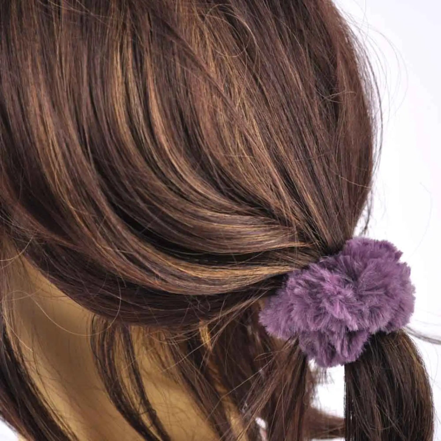 Woman wearing faux fur scrunchie with purple flower in hair