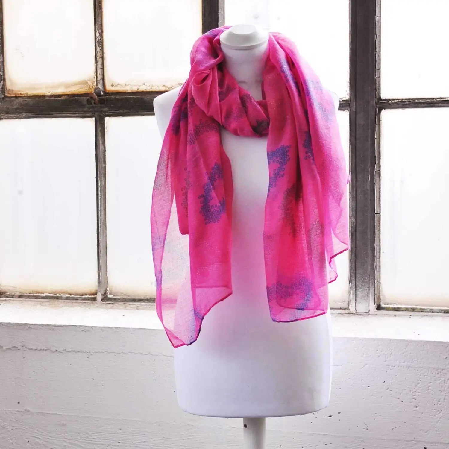 Oversized pink scarf with heart print on mannequin near window