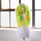 Oversized lightweight scarf with heart print and neon colours displayed on mannequin in front of window.