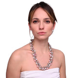 Woman wearing white dress and pink necklace.