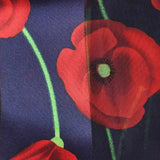 Close up of red poppy floral print scarf & gold plated ring set on navy background.