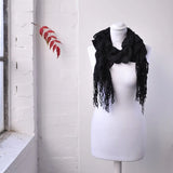 Lightweight knitted ruffled scarf on mannequin with red leaf background