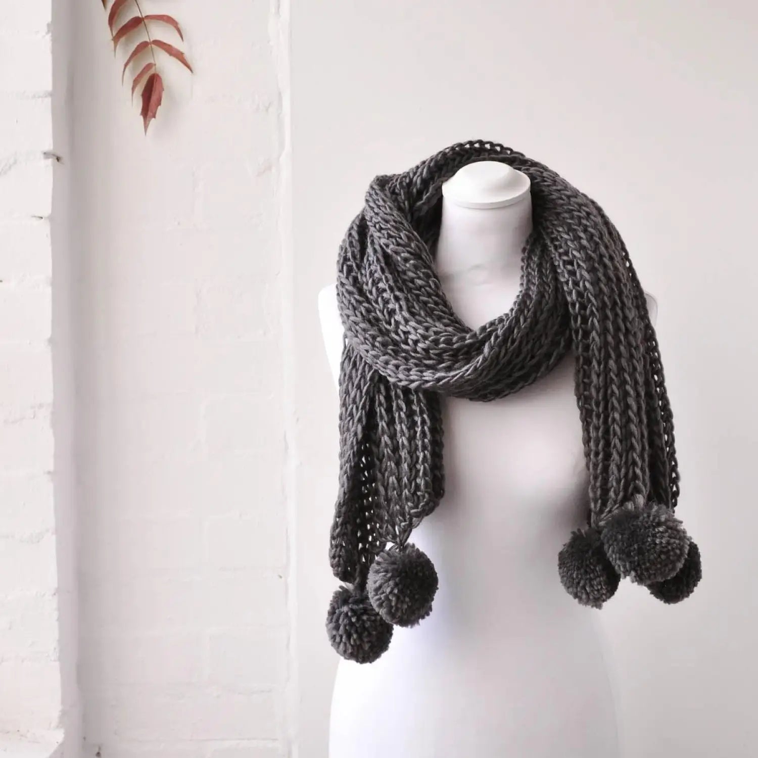 Chunky knit winter scarf on mannequin with pom poms