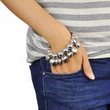 Woman wearing silver bead bracelet with rhinestone heart charm.