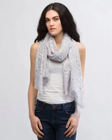 Woman wearing a white scarf with silver foil triangle print.