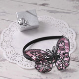 Pink butterfly Alice headband with sequins displayed on white doily
