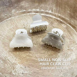 A pair of white sparkling small hair clips atop a wooden bowl from a set of 6 small hair claws