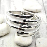 Stack of silver rings on white background, showcasing Striped Metal Hinged Bangle - Vintage-Inspired Bracelet.