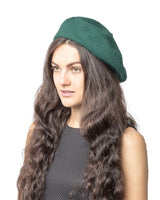 Woman with long brown hair in green hat, French wool beret fashion accessory.