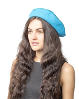 Woman with long brown hair wearing a blue French wool beret.