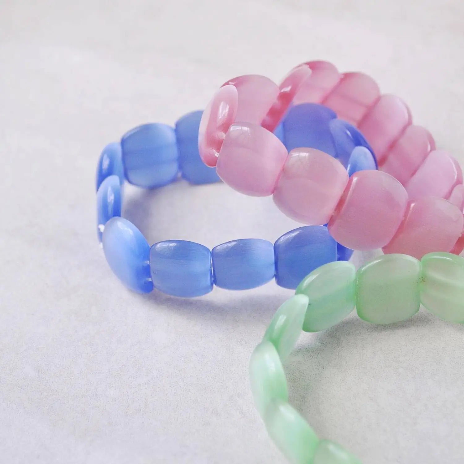 Pastel plastic bead bracelets on white surface