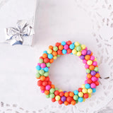 Colorful candy wreath on vibrant multi coloured bracelet with wood-effect plastic beads.