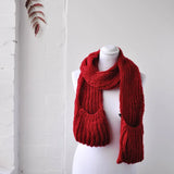 Chunky knitted winter scarf with pockets on mannequin against white brick wall